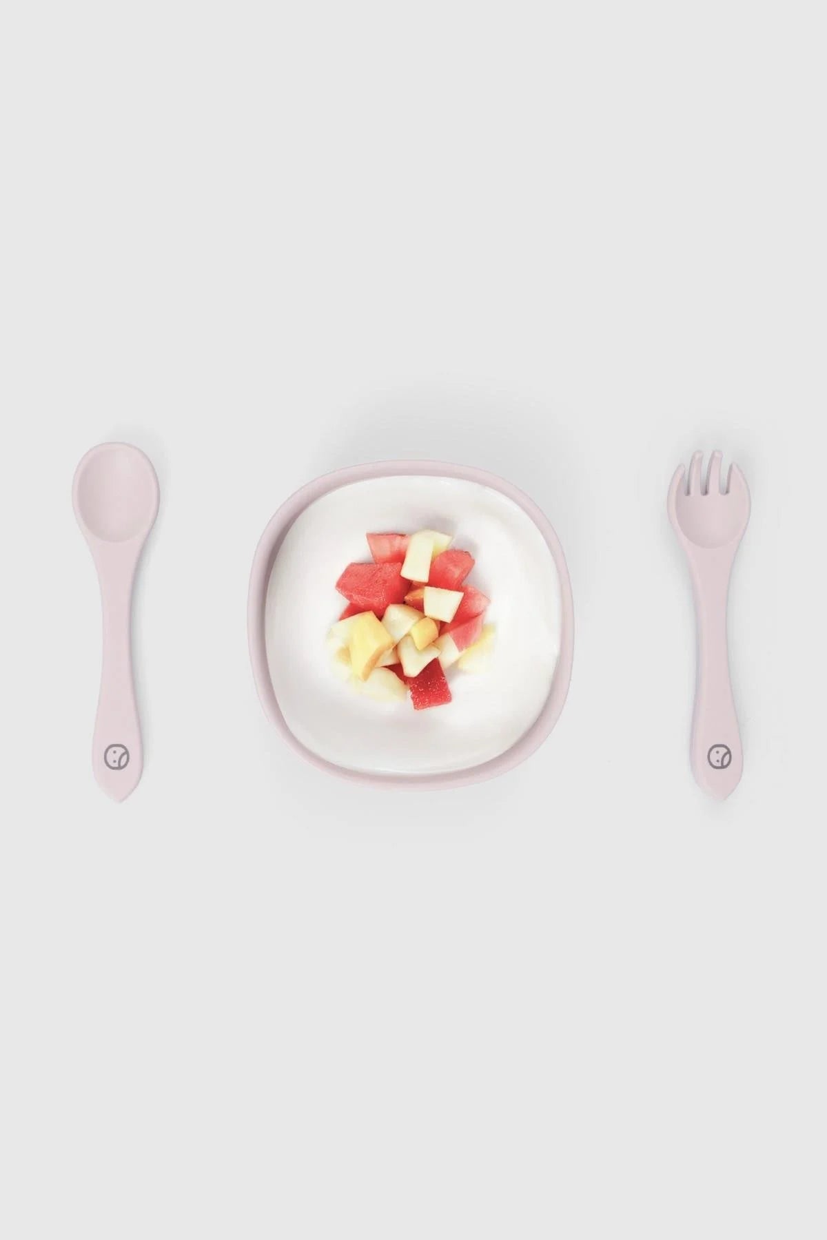 Silicone vacuum food plate and cutlery set in pink, featuring a bowl with fruit and a pink fork and spoon.
