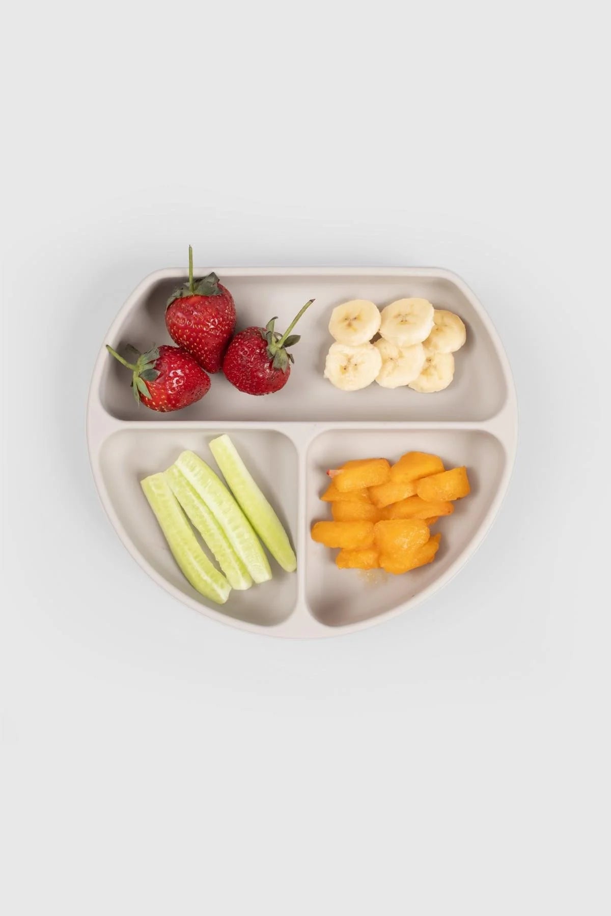 3 compartment baby feeding plate with lid in beige, filled with fruit and vegetable snacks.