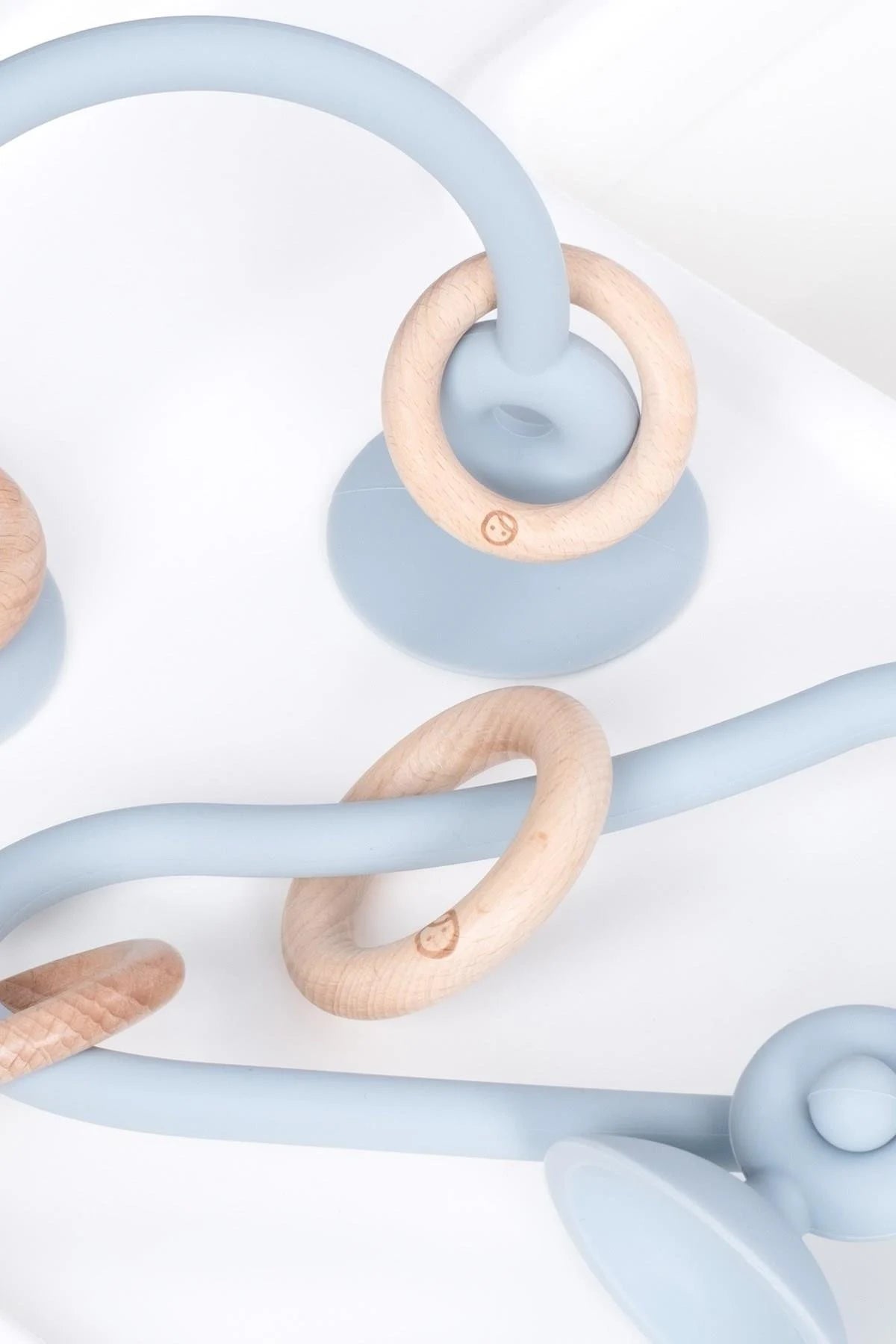 Silicone high chair toy for baby and toddler with wooden rings and suction base in blue color.