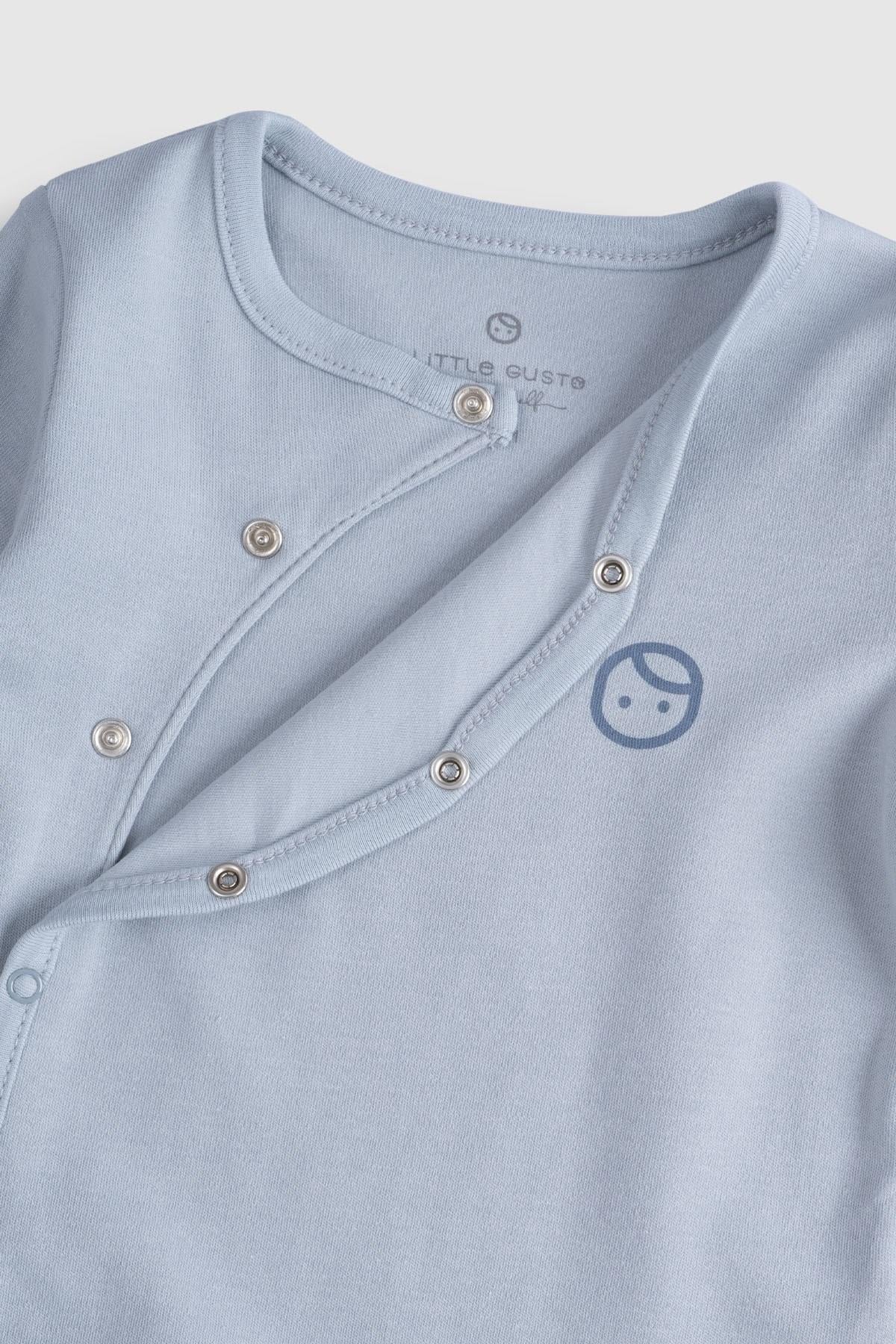 Close-up of blue organic cotton baby sleepsuit with snap buttons and a logo, perfect for infants.