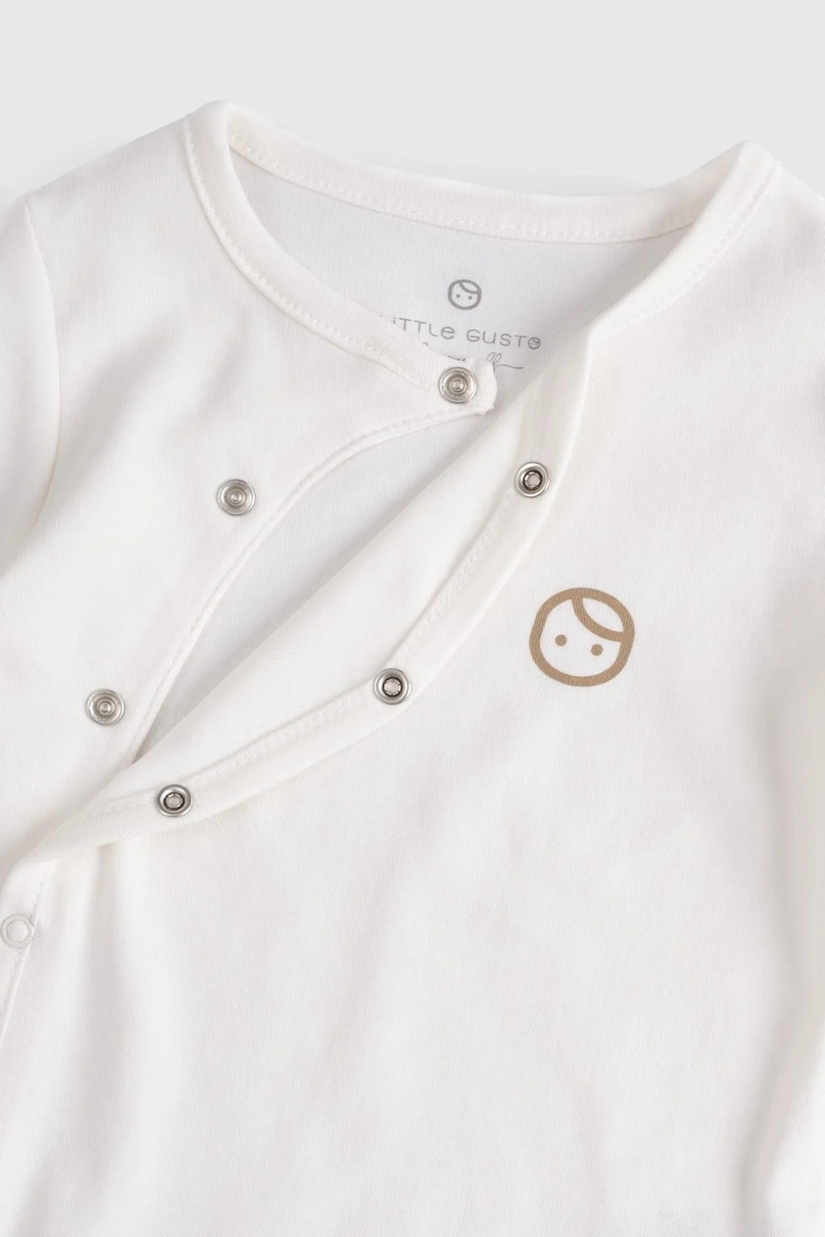 Organic cotton baby sleepsuit in white with snap buttons and cute logo, perfect for comfortable infant wear.