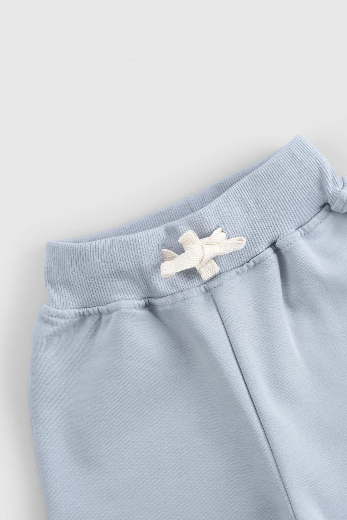Close-up of blue baby tracksuit pants showcasing ribbed waistband and embroidered detailing for comfort and style.