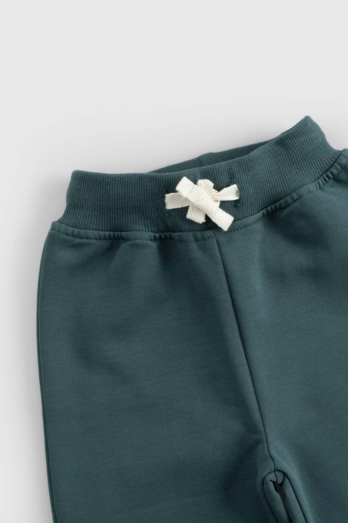 Close-up of ribbed waistband of organic cotton baby tracksuit set in green, featuring a soft texture and decorative bow.