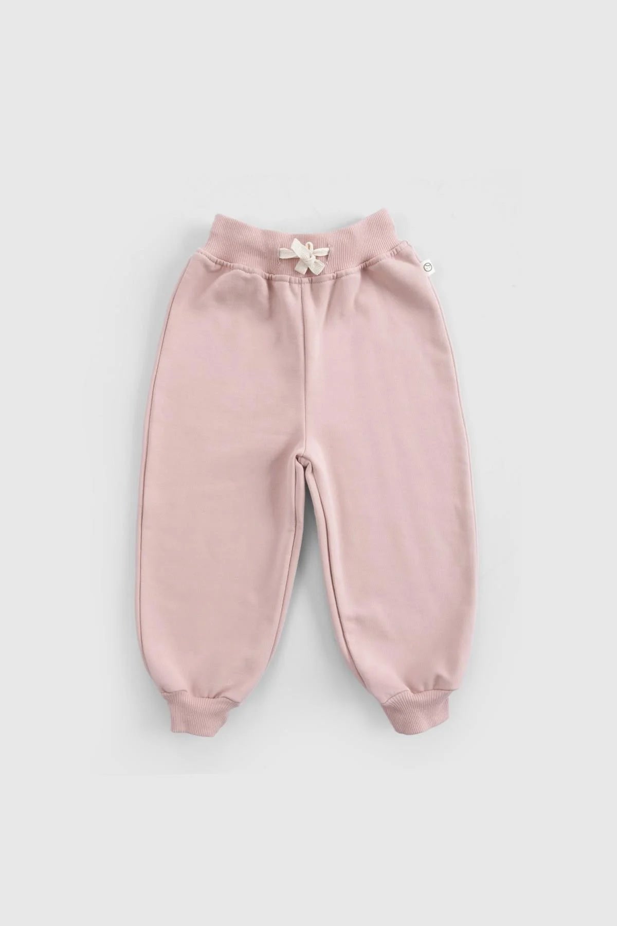 Pink organic cotton baby tracksuit pants featuring a ribbed waistband and elegant flower detail for stylish comfort.