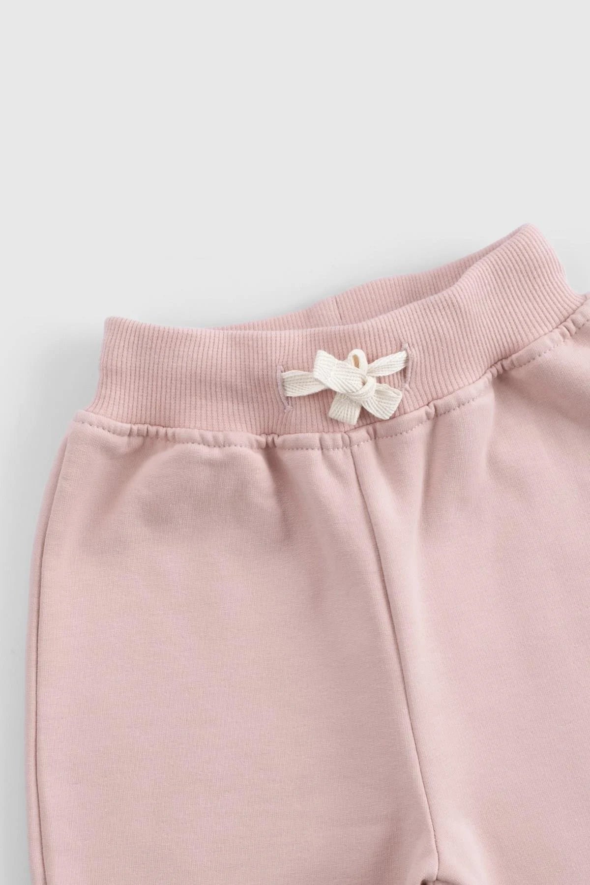 Close-up of the pink waistband of an organic cotton baby tracksuit set featuring a decorative bow.