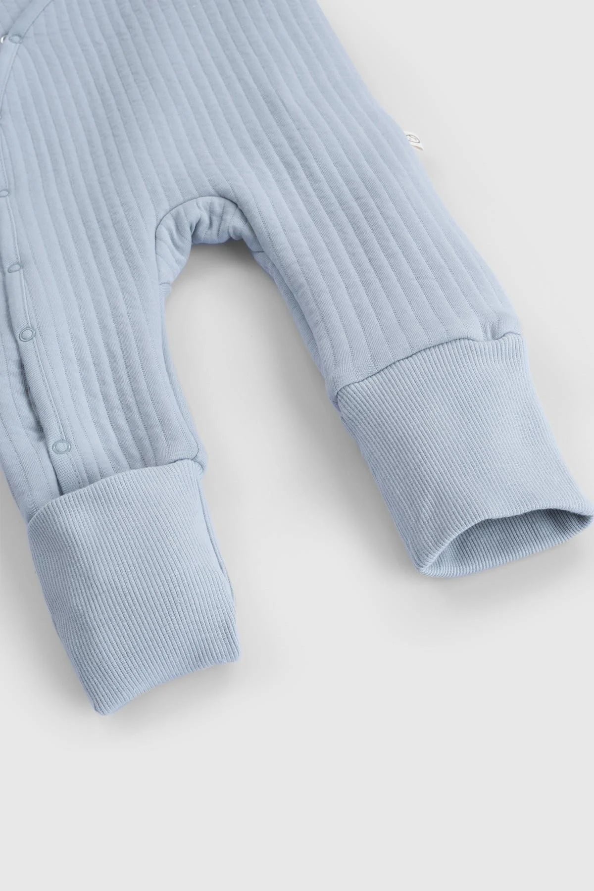 Close-up of blue organic cotton quilted sleepsuit, featuring ribbed fabric and fold-over cuffs.