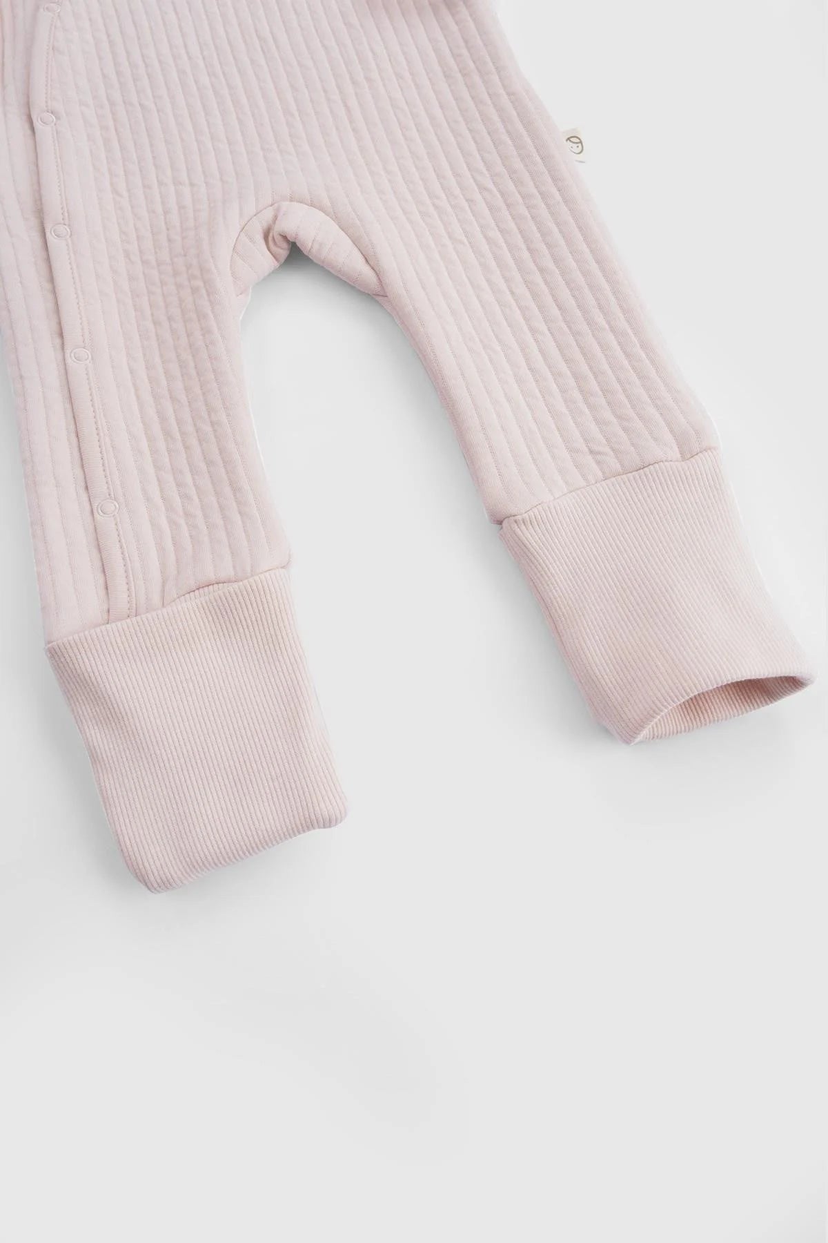 Close-up of the pink ribbed fabric and fold-over cuffs on the Little Gusto organic cotton quilted sleepsuit.