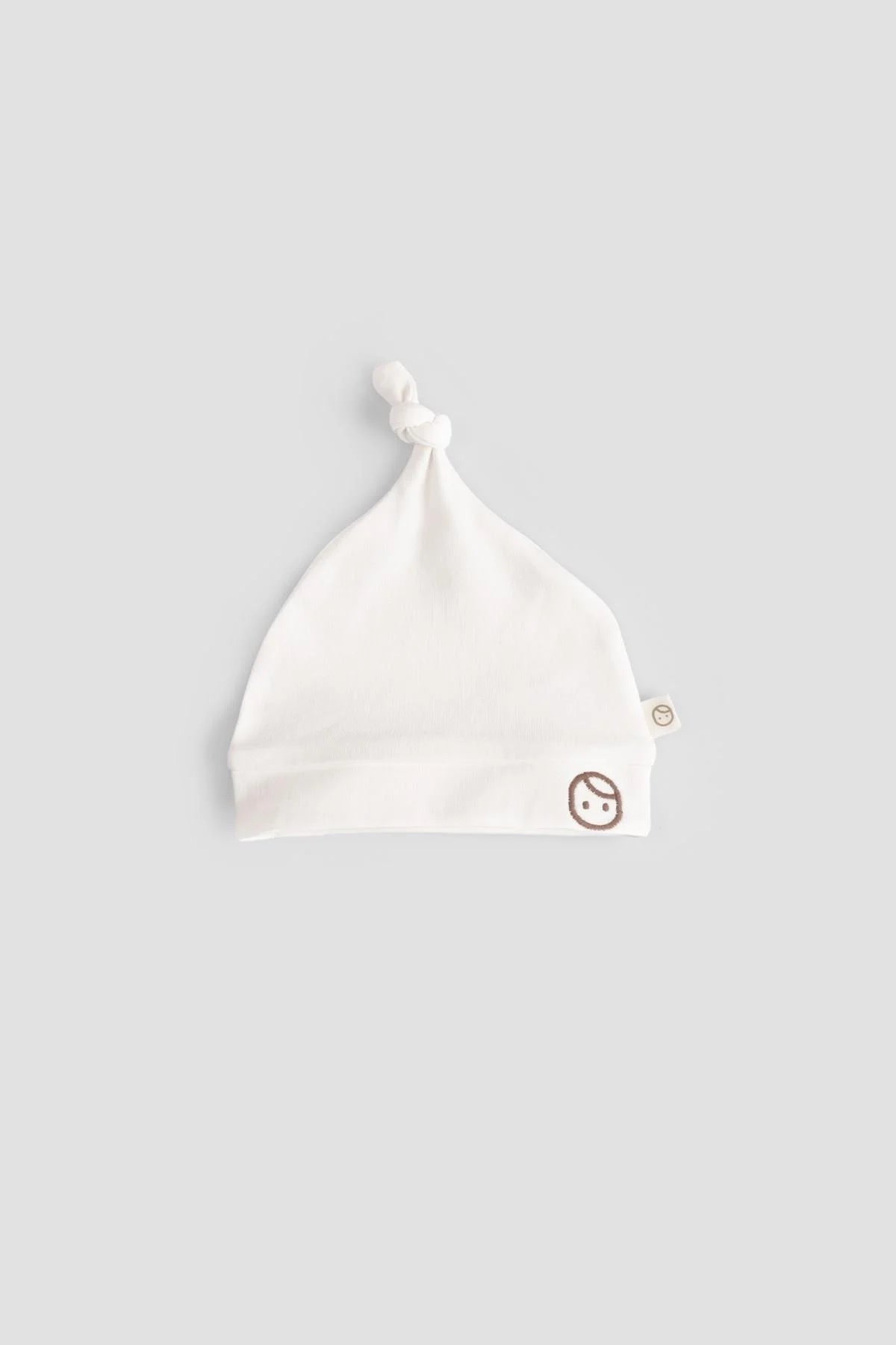 Organic cotton newborn hat in white with a playful design, perfect for ensuring comfort for delicate baby skin.