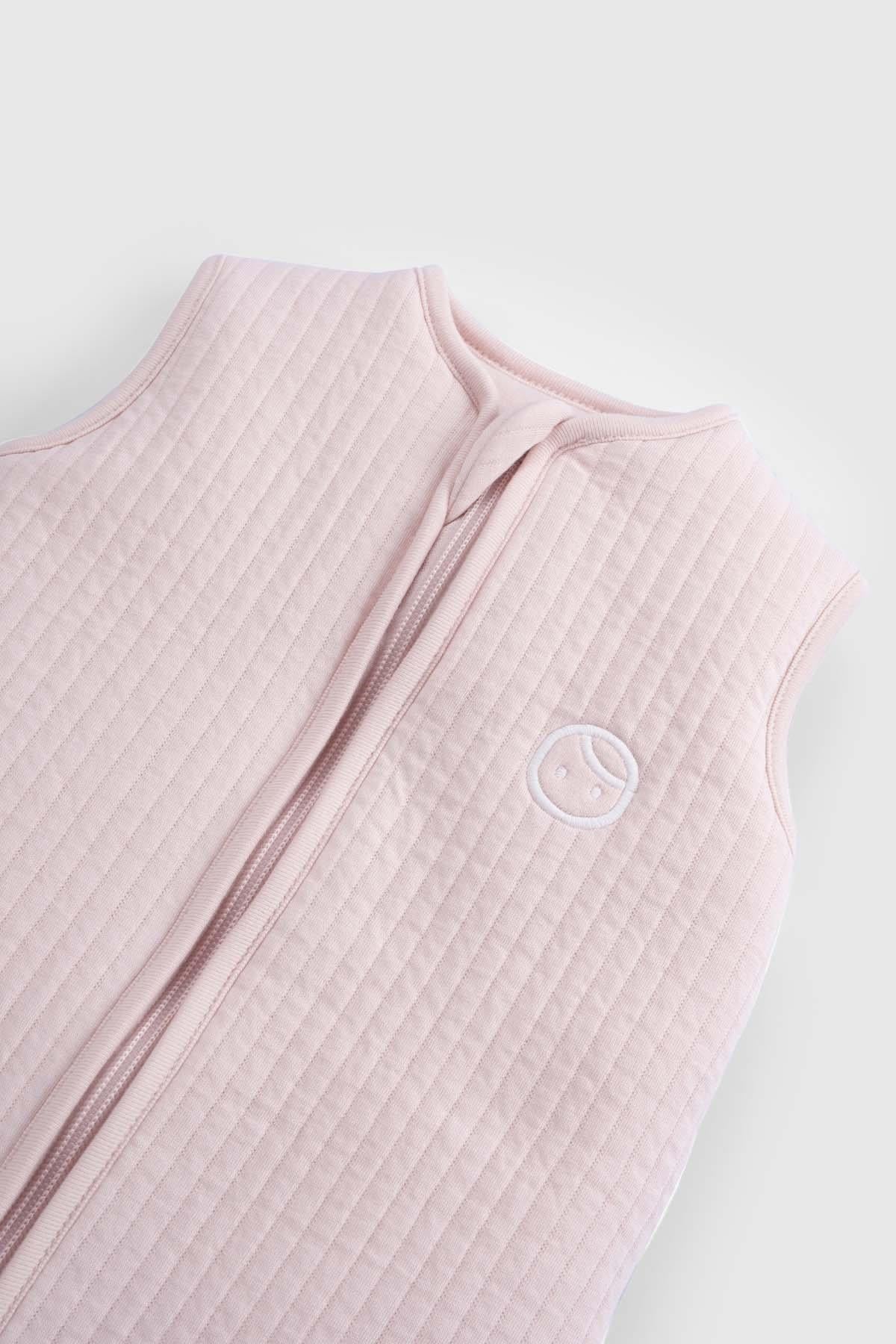 Pink organic cotton quilted sleeping bag for babies, featuring a sleeveless design and logo detail.
