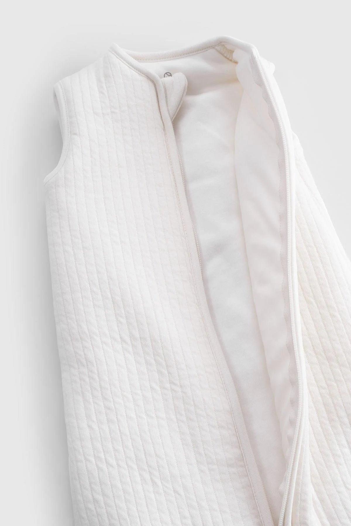 Organic cotton quilted sleeping bag in white, featuring a sleeveless design and soft padding for baby comfort.