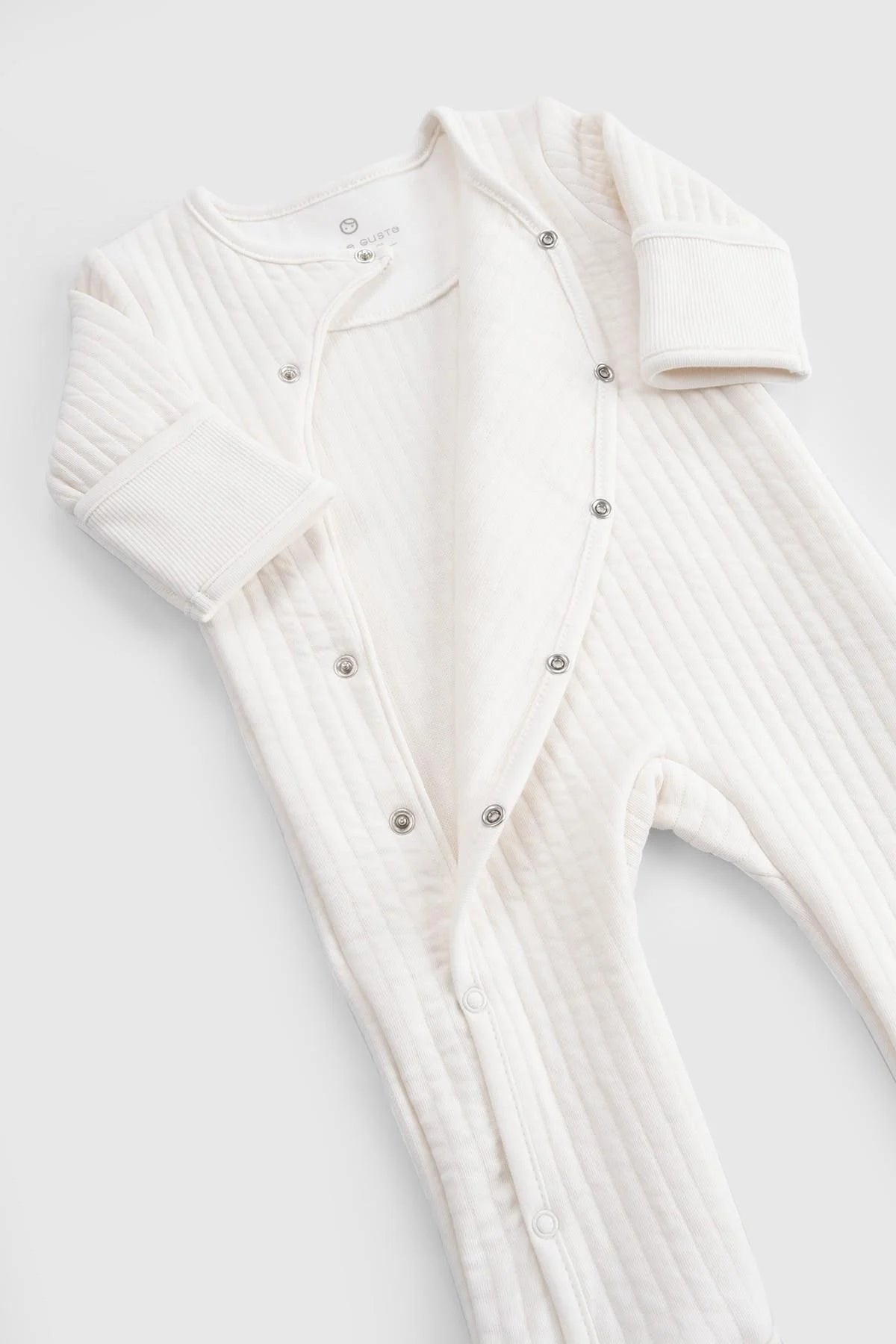 Organic cotton quilted sleepsuit in white, featuring soft padding and snap closures for comfort.