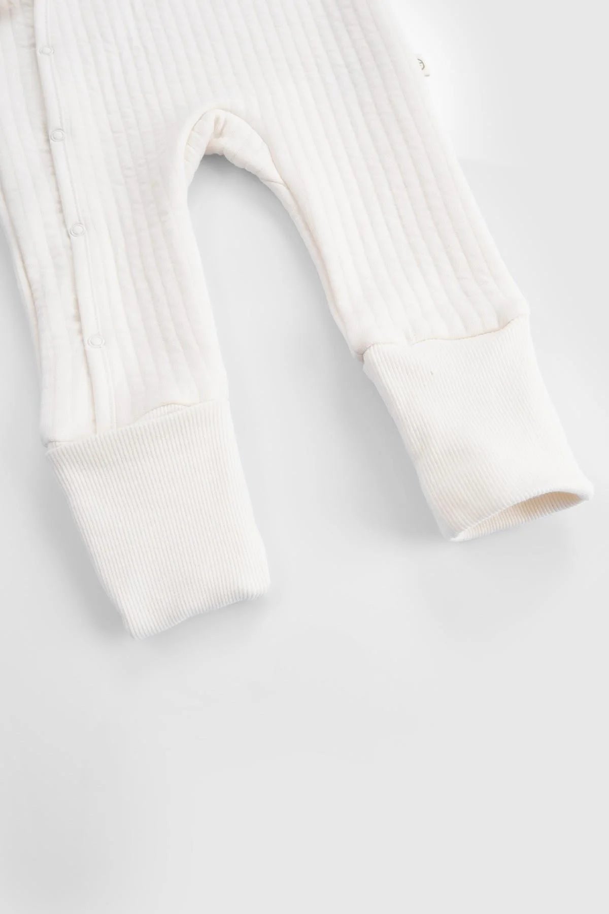 Detail of Little Gusto organic cotton quilted sleepsuit in white, showcasing its soft fabric and cozy cuffs.