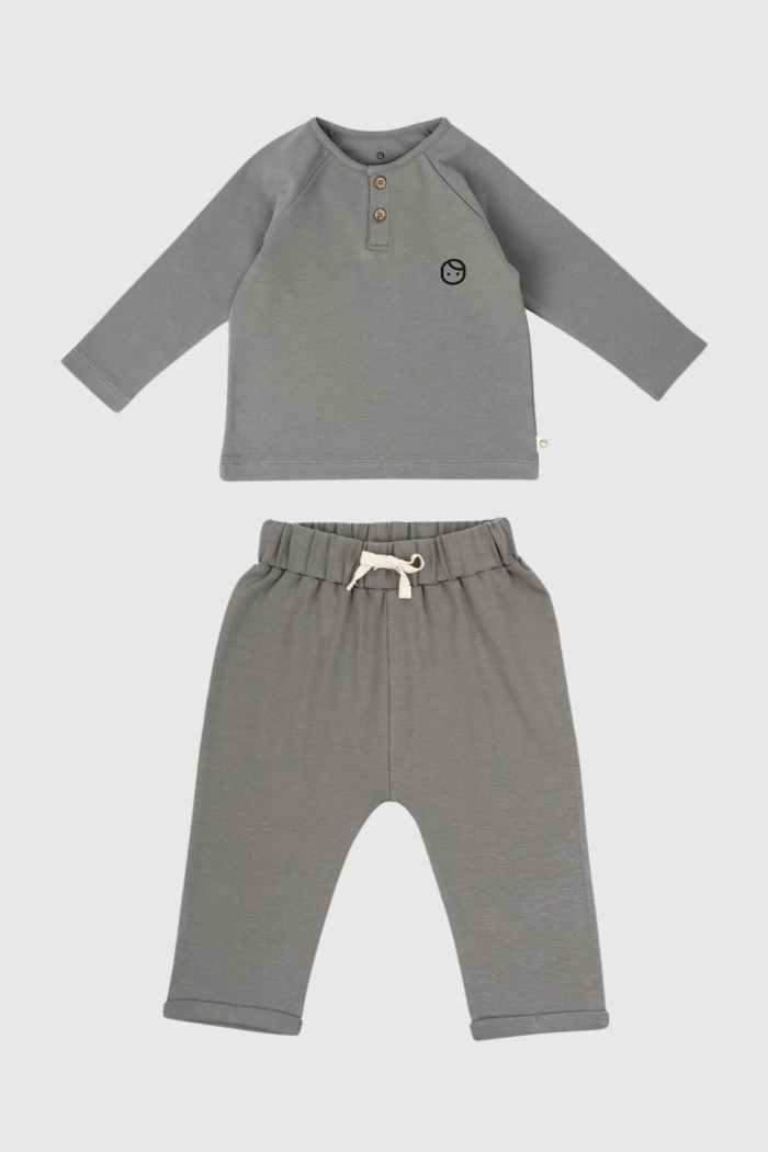 A grey organic cotton pyjama set consisting of a short-sleeved top and pants with a waist cord on the trousers.