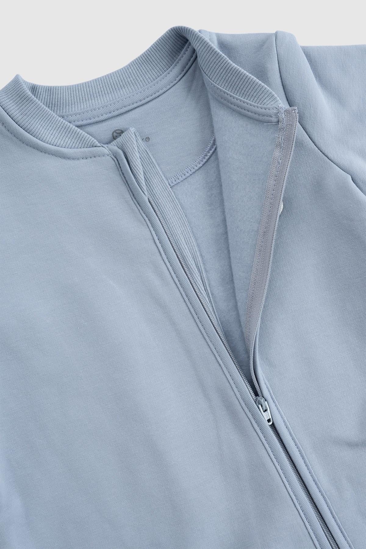 Close-up of an organic cotton zipped onesie in blue, showcasing its soft fabric and zipper detail.