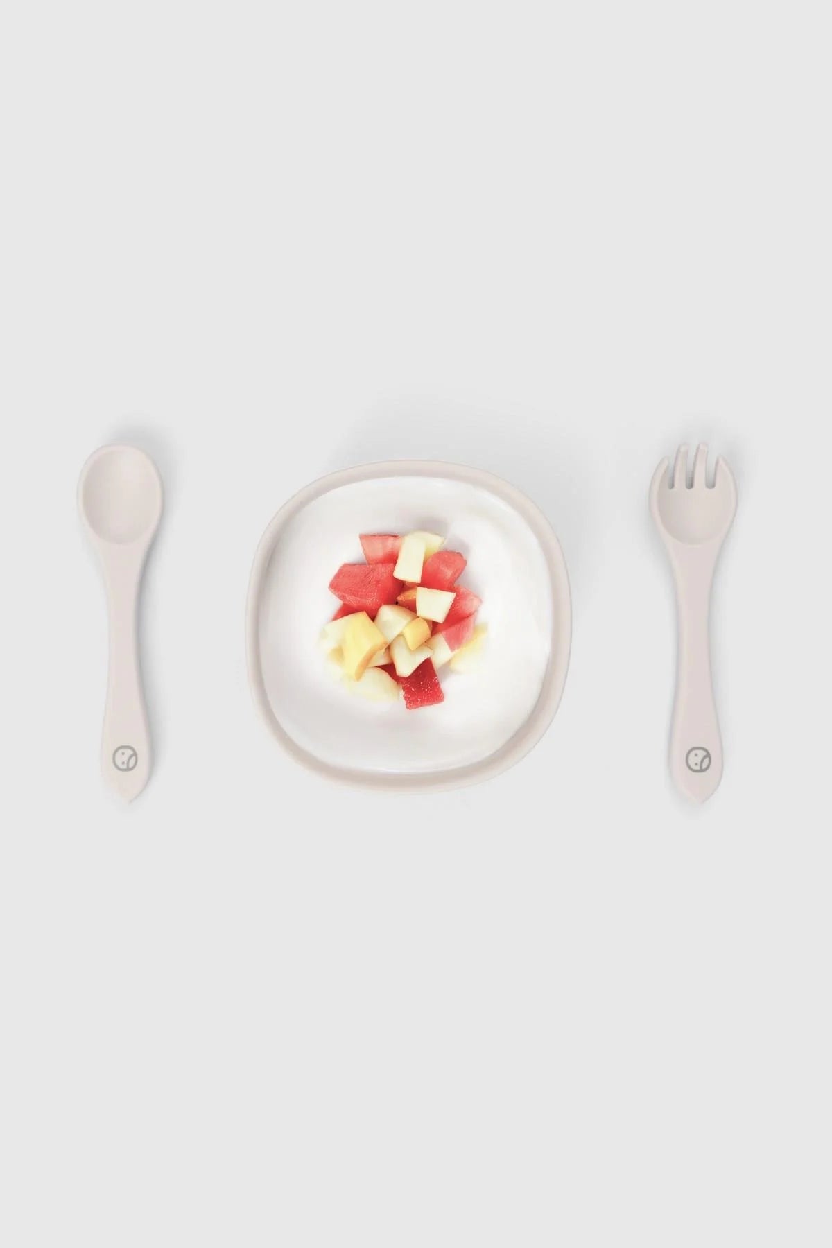 Silicone vacuum food plate with cutlery set featuring diced fruit for baby self-feeding in beige.